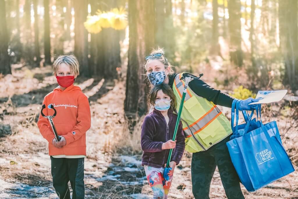 family in woods picking up trash