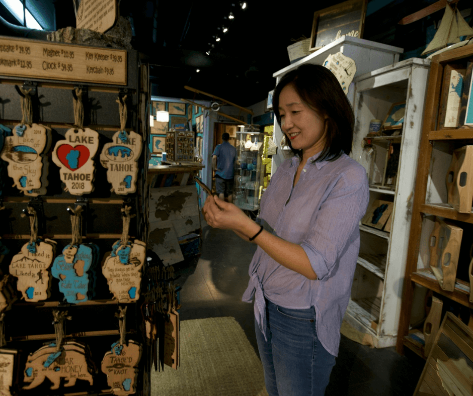 A woman holding a piece of wood art in a store.