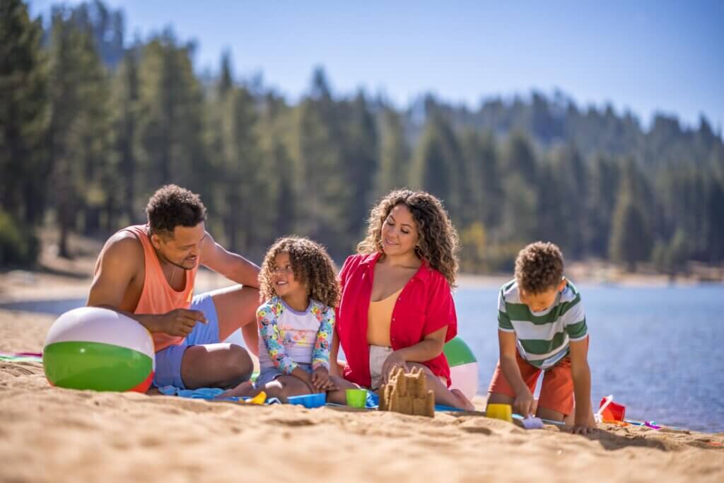 a family playing in the sand on a lake tahoe beach