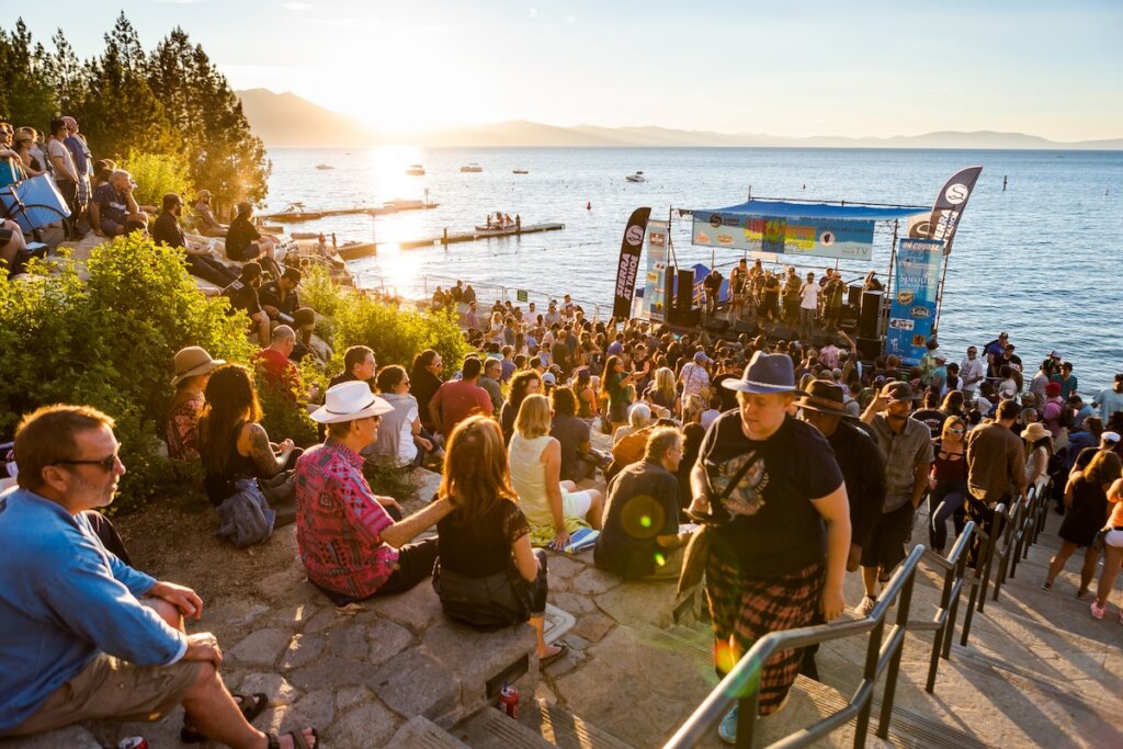 A crowd enjoy live music at Lake Tahoe while the sun sets.