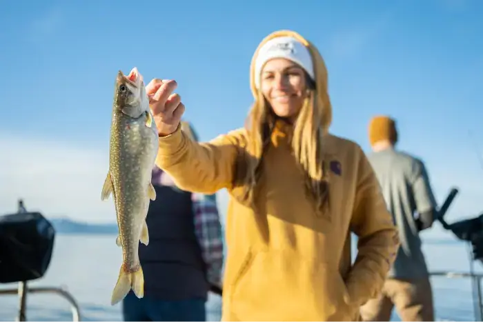 Woman holding up her catch while fishing in Lake Tahoe